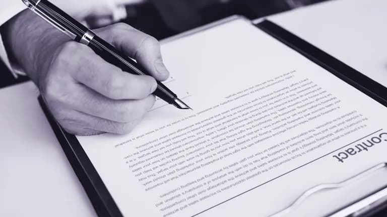 Assinatura de um contrato sobre a mesa, com caneta e documento.