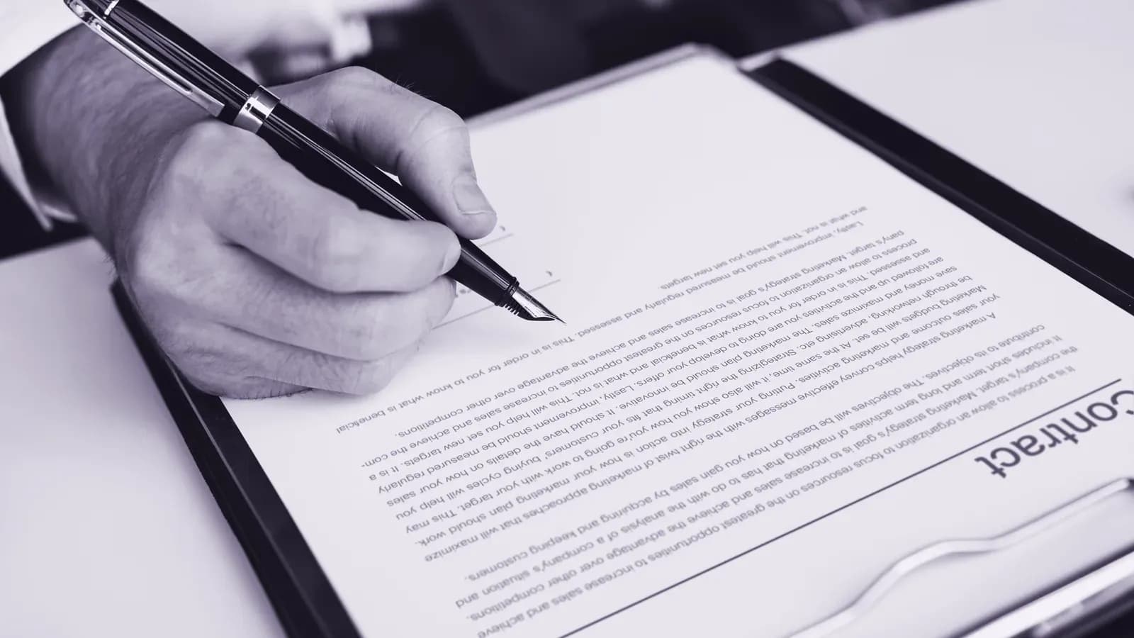 Assinatura de um contrato sobre a mesa, com caneta e documento.