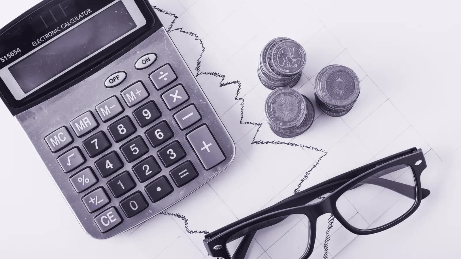 Calculadora, moedas e planilha sobre a mesa: o custo de contratar uma agência de marketing.